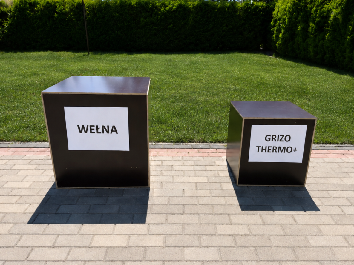 Dwa modele domków testowych — większy z napisem WEŁNA, mniejszy z napisem GRIZO THERMO+